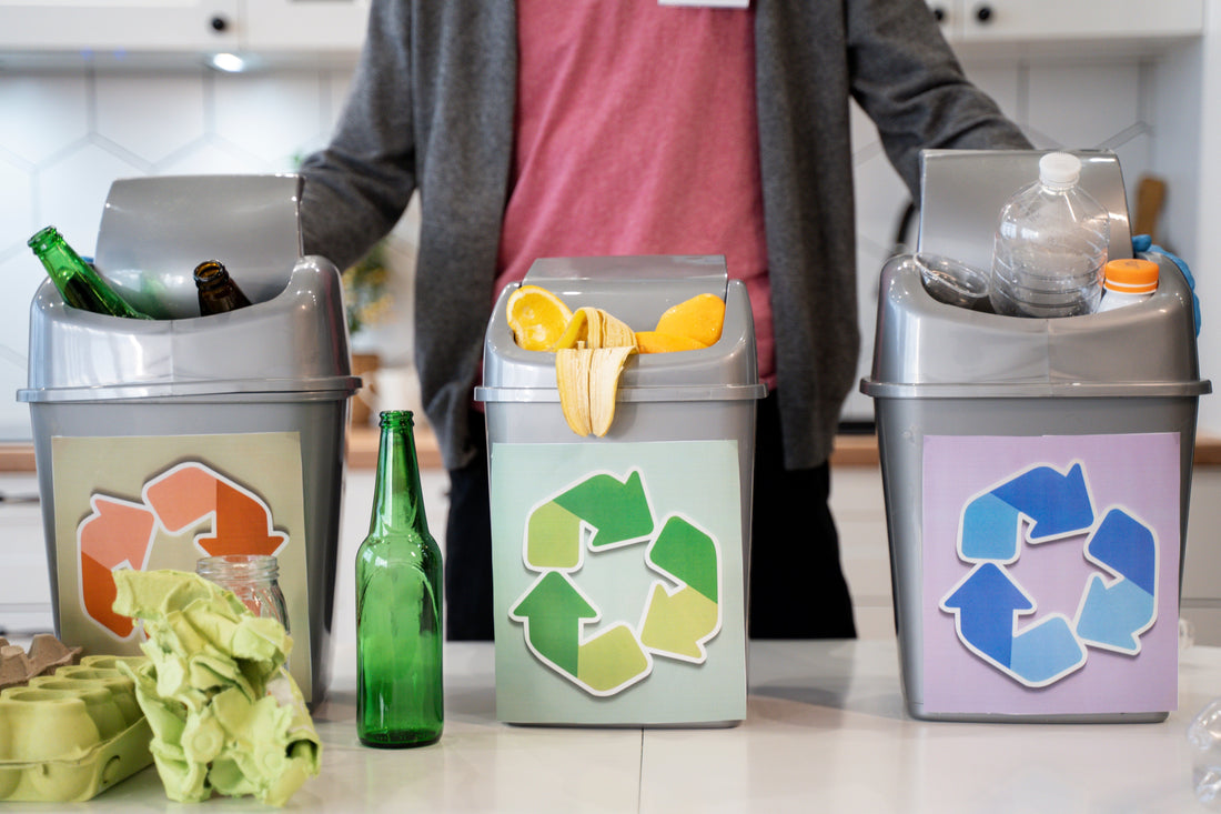 Household sorting trash and recycling into separate bins in a modern kitchen to reduce waste costs