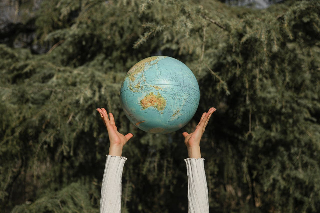 Earth Day sustainability concept with hands holding a globe outdoors, representing environmental protection and reducing waste